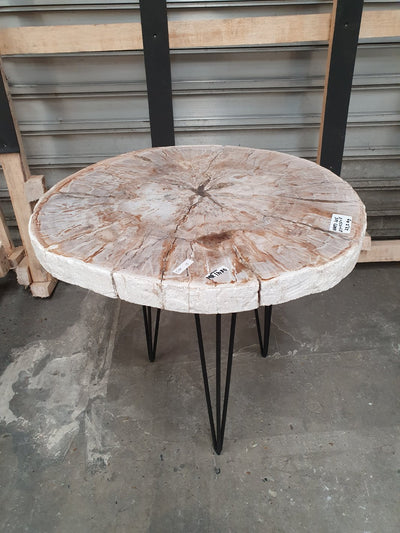 Salontafel van versteend hout met zwart metalen onderstel. Kleur van de versteend hout schijf is rozig met beige.